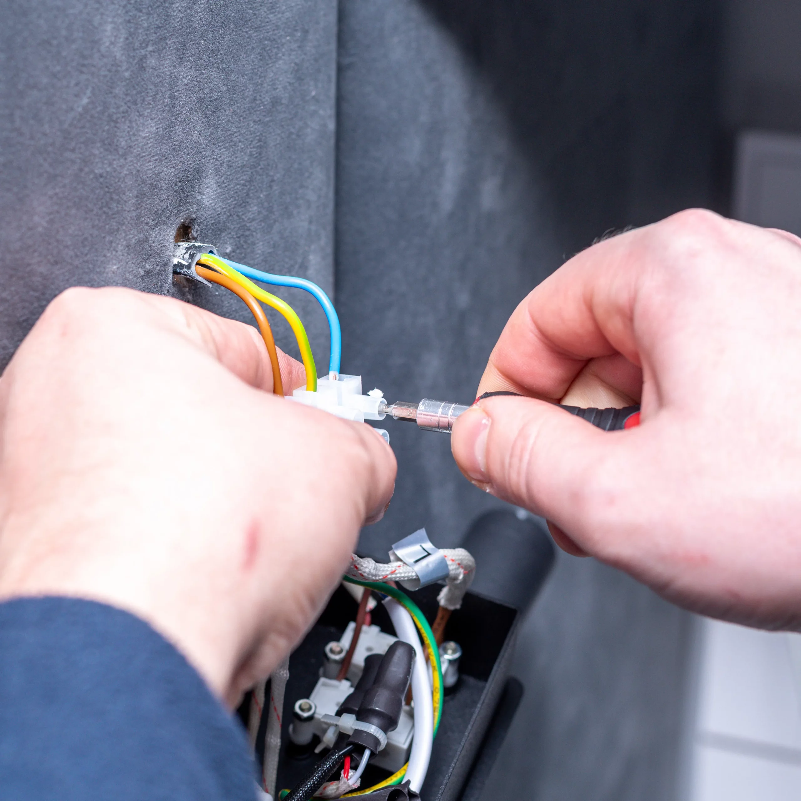 Säker och noggrann elinstallation Närbild på en elektriker som kopplar elkablar i en vägg med hjälp av en skruvmejsel.