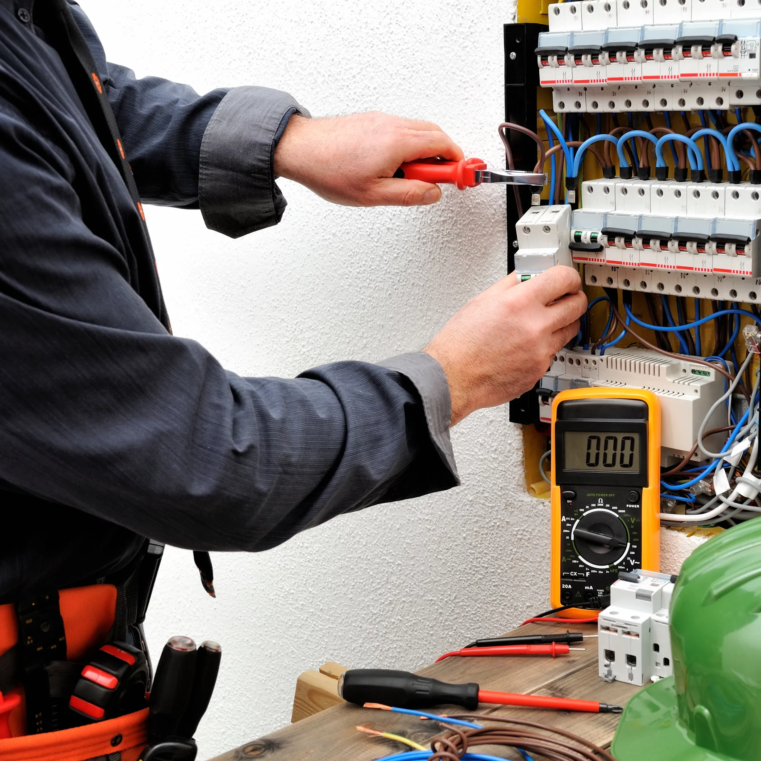 Professionell service av elcentral Elektriker installerar och kontrollerar säkringar i en elcentral med hjälp av verktyg och multimeter.